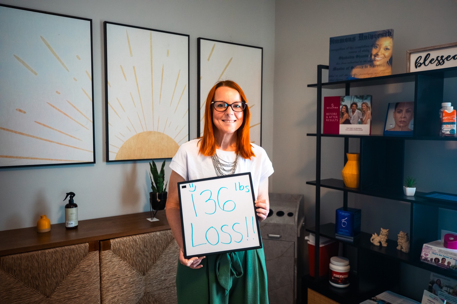 A smiling Cura patient holding a sign that reads 136 pounds lost